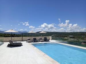 einen Pool mit Stühlen und Sonnenschirmen auf einer Terrasse in der Unterkunft Villa Kafkales Maleme - Heated Pool in Maleme