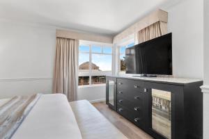 Schlafzimmer mit einem Bett, einem TV und einem Kamin in der Unterkunft Ascot Suites Morro Bay in Morro Bay