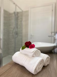 un mucchio di asciugamani con una rosa sopra in bagno di PALM House Affitta camere a Tortolì