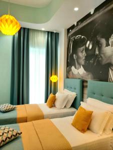 2 Betten in einem Zimmer mit einem großen Bild an der Wand in der Unterkunft Nostalgia Retro Suites in Naxos Chora
