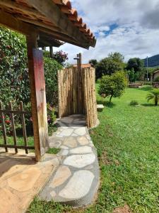 a garden with a wooden gate and a walkway at Recanto das Flores in São Thomé das Letras