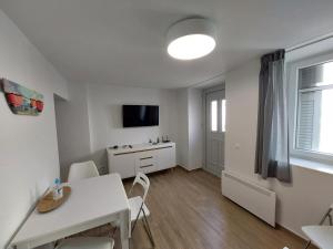 a living room with a white table and a tv at Sweet & Cosy Αpartment in Chora's old town in Andros