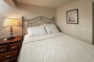 een slaapkamer met een wit bed met een lamp en een dressoir bij Memphis Belvedere Suites Upper Queen loft 1 Bedroom in Memphis