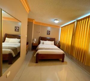 Habitación de hotel con 2 camas y espejo en Apart Hotel Hamilton, en Manta