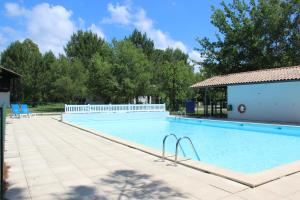 a large swimming pool with blue chairs and a building at La Cachette du Lac - Parenthèse nature entre piscine, lac & océan in Lacanau