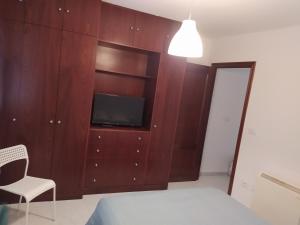 a bedroom with a tv in a wooden cabinet at Vivienda en el casco histórico de Baiona in Baiona