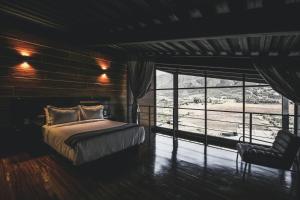 a bedroom with a bed and a chair and a window at Origen75 Loft - Villas - Skypool - Viñedo, Valle de Guadalupe in Valle de Guadalupe