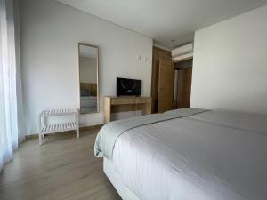a white bedroom with a bed and a television at Fátima Apartment - 1min Santuário in Fátima