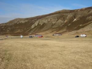 un campo con coches estacionados frente a una montaña en Ásbrandsstadir Cottage, en Vopnafjörður