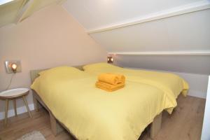 una piccola camera da letto con un letto giallo con una coperta gialla di Casa Feliz a Egmond aan Zee