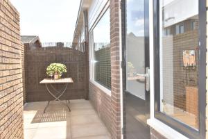 a small balcony with a table and a window at Casa Feliz in Egmond aan Zee
