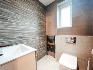 een badkamer met een wastafel, een toilet en een raam bij Beechwood Park by Solace Stays in Newport