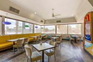 un restaurante con mesas, sillas y ventanas en Best Western Royal Sun Inn & Suites, en Tucson