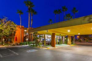 een lege parkeerplaats voor een gebouw met palmbomen bij Best Western Royal Sun Inn & Suites in Tucson