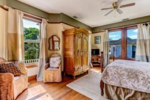 a bedroom with a bed and a couch and windows at Island Charm1908 classic in the heart of downtown in Fernandina Beach