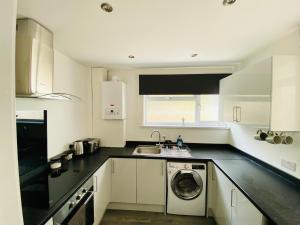 a kitchen with a sink and a washing machine at Emerald Properties UK 4 bedrooms - Swansea City Centre, close to beaches! in Swansea