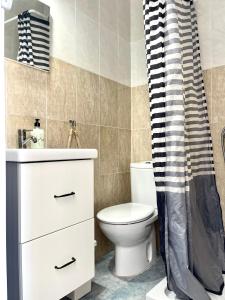 a bathroom with a toilet and a sink and a shower curtain at Atte's house, Pozo Izquierdo in Pozo Izquierdo