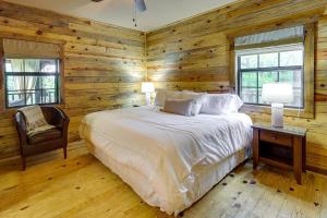 a bedroom with a bed and a chair and windows at Beaver Lake Vacation Rental with Private Hot Tub! in Eureka Springs