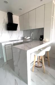a white kitchen with a counter and a stool at Mariana Suites in San Roque