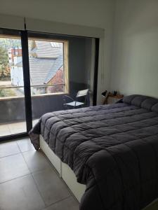 ein Schlafzimmer mit einem großen Bett und einem großen Fenster in der Unterkunft Para quedarse - SalePatagonia in San Martín de los Andes