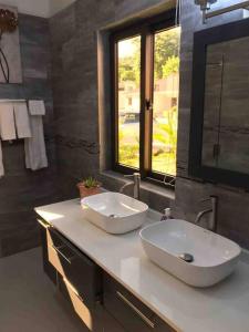 Baño con 2 lavabos blancos en una encimera en Sun Shine Luxury Villas 2 bedroom Pool & Gym Ocho Rios St Ann, en Ocho Ríos