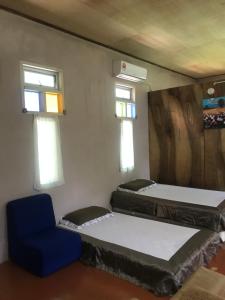 a room with two beds and a blue chair at Anjung Afilia 1 in Kuala Kangsar