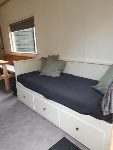 1 dormitorio con 1 cama blanca con colchón negro en Natuurchalet de Das, en Wehl