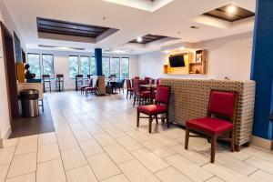 un comedor con sillas rojas y un bar en Holiday Inn Express Hotel & Suites Goshen, an IHG Hotel, en Goshen