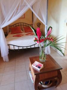 a bedroom with a bed with a vase of flowers on a table at Bigouz résidence la plage de l'anse Caritan in Sainte-Anne