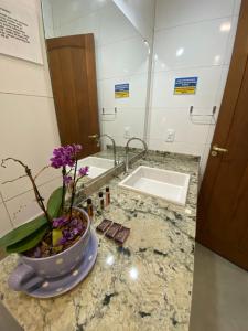 baño con lavabo y jarrón con flores púrpuras en Pousada Arraial Charme en Arraial d'Ajuda