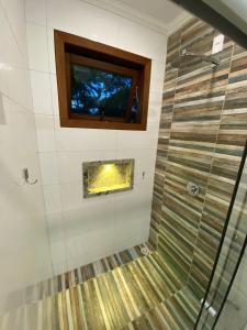 a bathroom with a glass shower with a window at Pousada Arraial Charme in Arraial d'Ajuda
