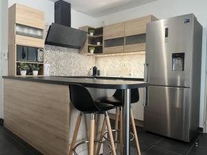 una cucina con frigorifero in acciaio inossidabile e sgabelli da bar di Appartement T2 vue panoramique sur Annecy a Seynod