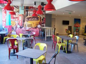 ibis Styles Vierzon في فييرزو: مطعم على الطاولات والكراسي وقطار على الحائط