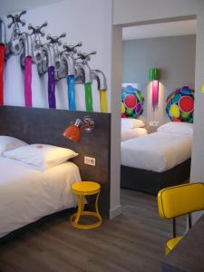 ibis Styles Vierzon في فييرزو: غرفة فندق بسريرين مع مظلات على الحائط