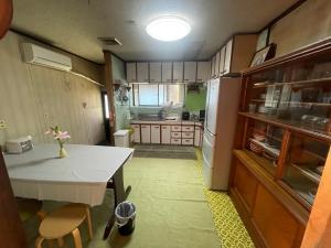 a small kitchen with a table and a refrigerator at 高島市マキノ町民泊お得 in Takashima