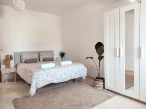 a white bedroom with a bed and a mirror at La casita in Arona