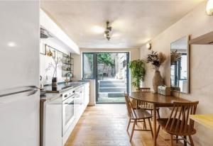 a kitchen with a table and chairs and a dining room at Modern flat with KING bed, garden & outdoor dining in London
