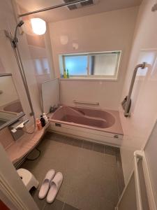 y baño con bañera, ventana y 2 zapatillas. en 高島市マキノ町民泊お得, en Takashima