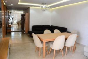 AGADIR BAY Appartement de haut standing 140m2 في أغادير: غرفة طعام مع طاولة وكراسي بيضاء