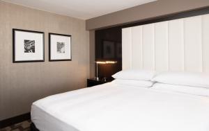 um quarto com uma grande cama branca e duas fotografias emolduradas em Beverly Hills Marriott em Los Angeles