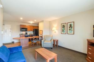 Western Slope Suites Parachute في باراشوت: غرفة معيشة مع أريكة زرقاء ومطبخ