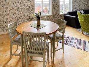 une table à manger avec des chaises et un vase avec des fleurs. dans l'établissement Holiday home KARLSKRONA IV, à Karlskrona