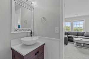 La salle de bains blanche est pourvue d'un lavabo et d'un miroir. dans l'établissement Seas the Moment home, à Emerald Isle