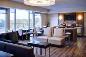 uma sala de estar com cadeiras e um bar com janelas em Detroit Metro Airport Marriott em Romulus