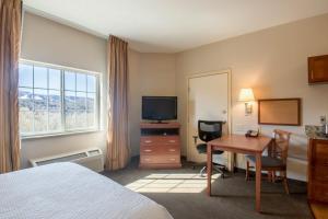 降落伞Western Slope Suites Parachute的配有床、书桌和电视的酒店房间