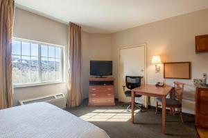 Habitación de hotel con cama, escritorio y TV. en Western Slope Suites Parachute, en Parachute