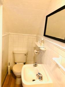 a white bathroom with a toilet and a sink at AC Hideout in Rochford