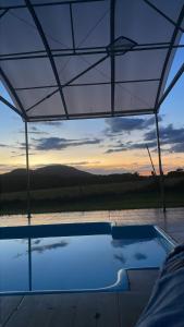 a swimming pool under a tent with a sunset in the background at Chácara recanto Feliz in Pirenópolis
