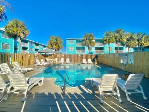 a swimming pool with white chairs and a building at Lani Kai Village 211 by ALBVR - Beautifully Remodeled Condo with Indirect Gulf views from Balcony! in Gulf Shores