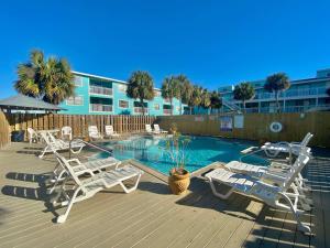 a deck with chairs and a swimming pool in front of a building at Lani Kai Village 211 by ALBVR - Beautifully Remodeled Condo with Indirect Gulf views from Balcony! in Gulf Shores